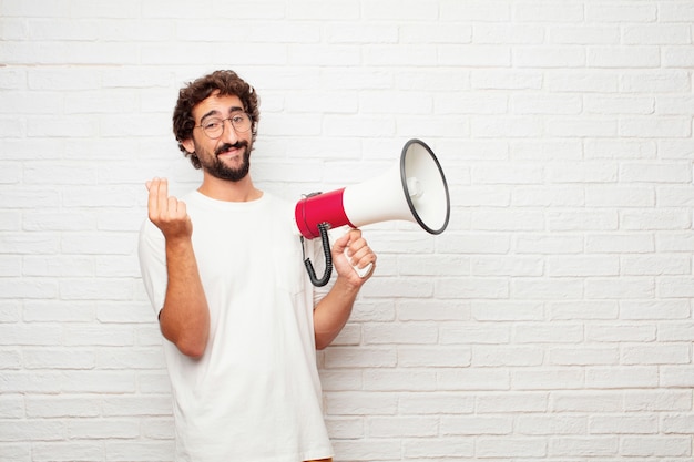 Jeune homme fou avec un mégaphone contre le mur de briques.