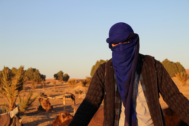 Un jeune homme avec le foulard berbère dans le désert de Merzouga