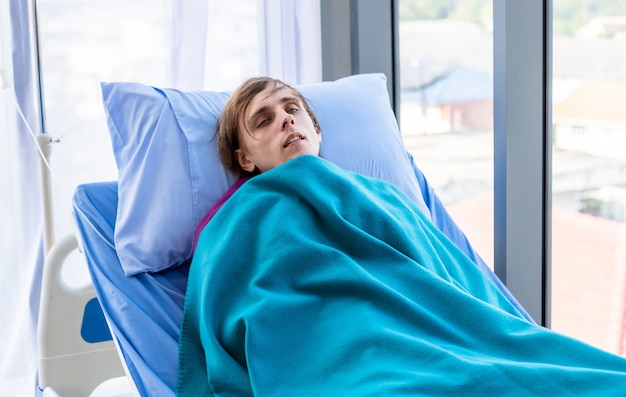 Le jeune homme a des frissons de fièvre, le patient est allongé sur le lit de ses secousses dans le fond de l'hôpital de la chambre.