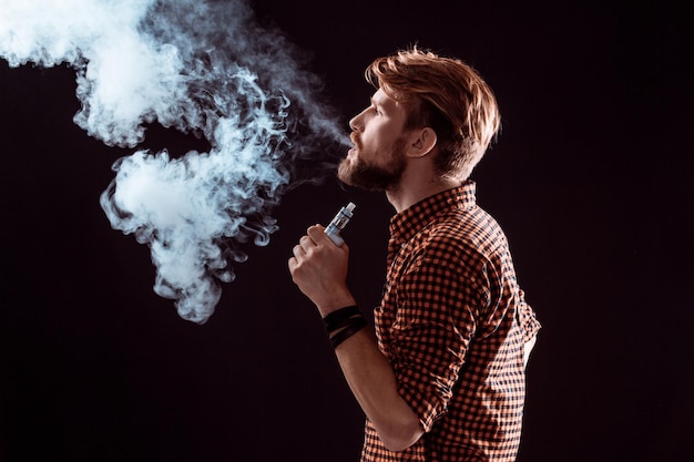 Jeune homme fumant une cigarette électronique