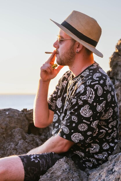 Jeune homme fumant un joint face à la mer