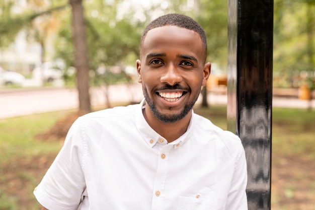 Photo jeune homme gai vous regarde avec un sourire à pleines dents blanc tout en se tenant dans un environnement naturel