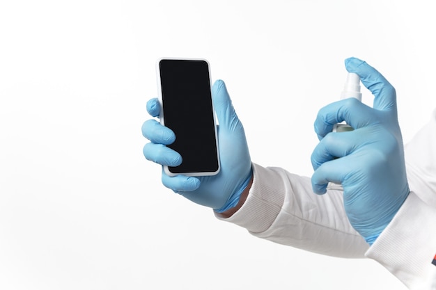 Jeune homme avec des gants bleus désinfectant le gadget