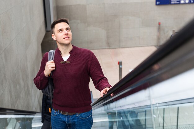 Jeune homme à la gare sur l&#39;escalator