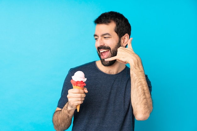 Jeune homme avec une glace au cornet sur bleu faisant un geste de téléphone. Rappelez-moi signe