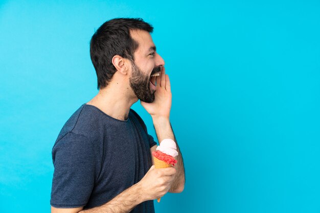 Jeune homme avec une glace au cornet sur bleu isolé