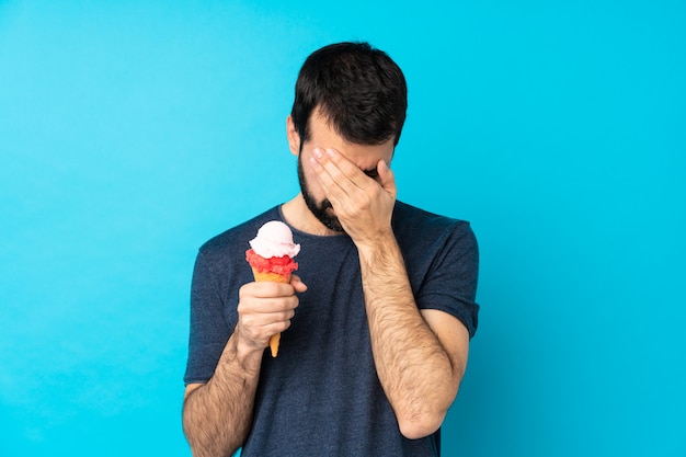 Jeune homme avec une glace au cornet sur un mur bleu isolé avec une expression fatiguée et malade