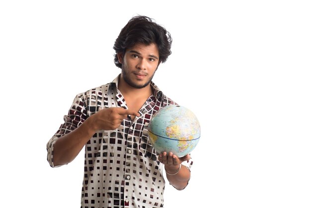 Jeune homme avec un globe terrestre sur un blanc.