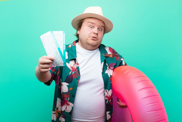 Jeune homme de grande taille avec un beignet gonflable contre un mur plat