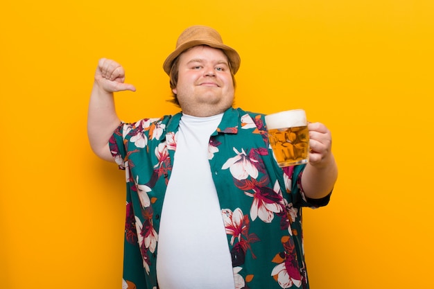 Jeune homme de grande taille avec une pinte de bière contre un mur plat