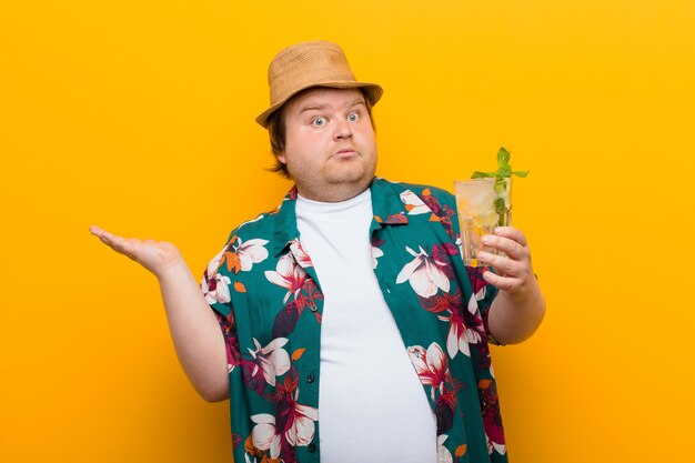 Jeune Homme De Grande Taille Avec Un Verre De Mojito Contre Un Mur Plat