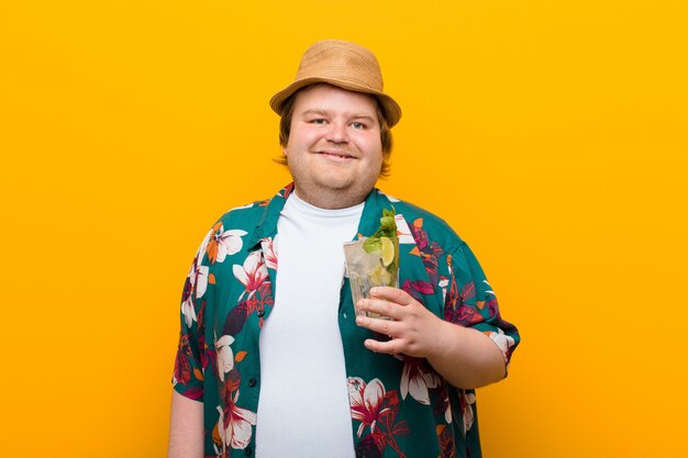 Jeune homme de grande taille avec un verre de mojito contre un mur plat