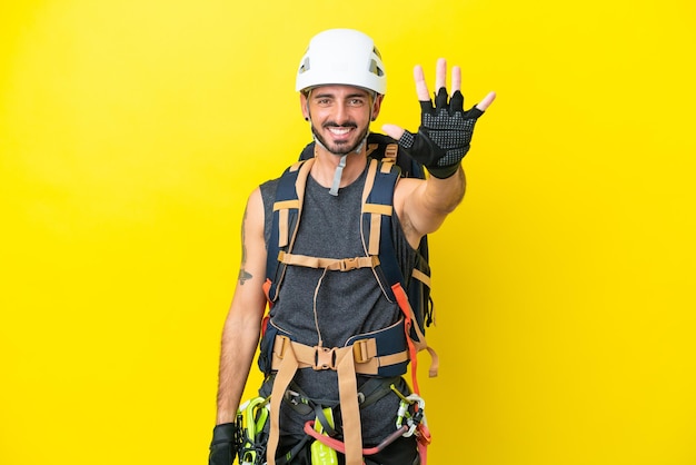 Jeune homme grimpeur caucasien isolé sur fond jaune comptant cinq avec les doigts