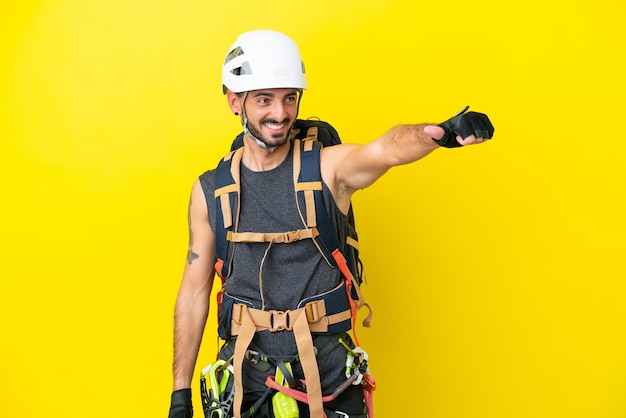 Jeune homme grimpeur caucasien isolé sur fond jaune donnant un geste du pouce levé