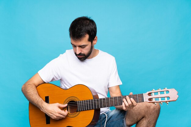 Jeune homme avec guitare sur bleu isolé