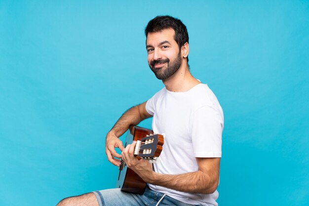 Jeune homme avec guitare sur bleu isolé