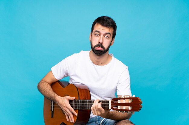 Jeune homme à la guitare avec une expression triste et déprimée