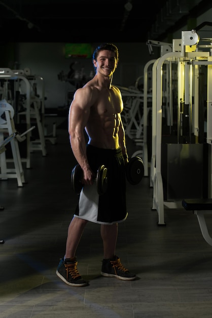 Jeune homme avec des haltères exerçant des biceps