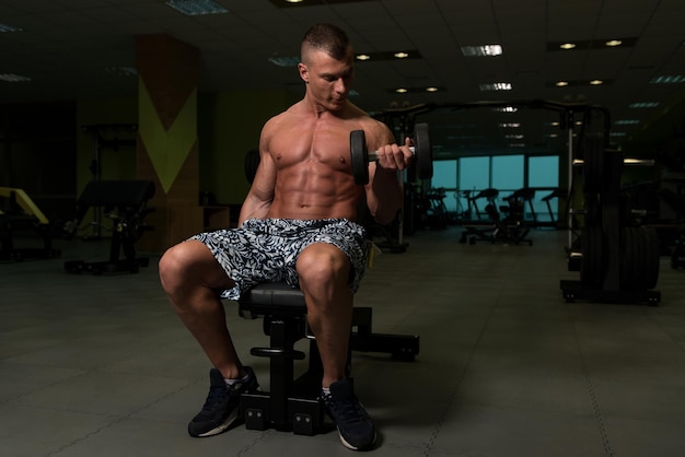 Jeune homme avec des haltères exerçant des biceps