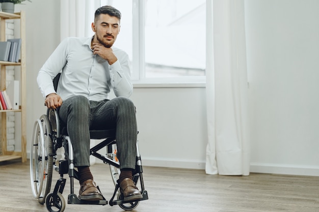 Jeune homme handicapé assis dans un fauteuil roulant près de la fenêtre