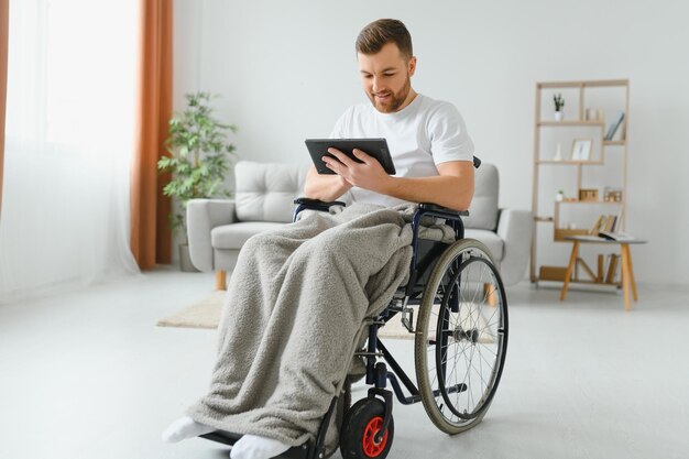 Jeune homme handicapé moderne en fauteuil roulant ayant un appel vidéo