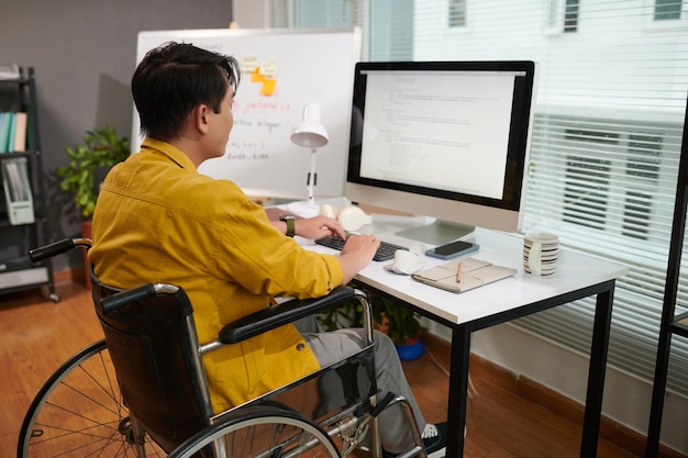 Jeune homme handicapé trouvant et résolvant des bugs dans des programmes informatiques