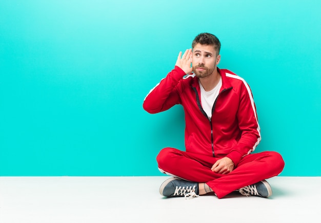 Jeune homme handosme air sérieux et curieux, à l'écoute, en essayant d'entendre une conversation secrète ou des potins, l'écoute contre le mur de couleur plat