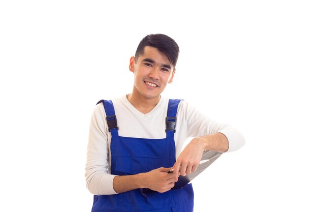 Jeune homme heureux en chemise blanche et combinaison bleue tenant un stylo blanc et un dossier noir