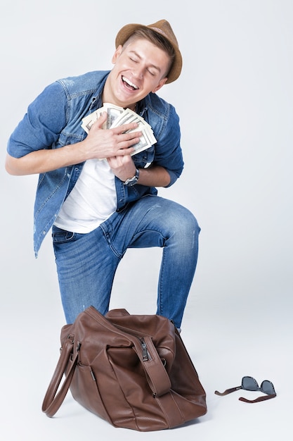 Jeune homme heureux dans un chapeau a trouvé de l'argent dans un sac en cuir