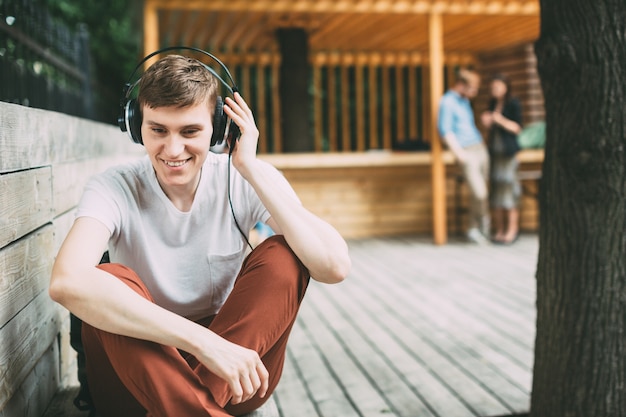 Jeune homme heureux dans les écouteurs à l'extérieur