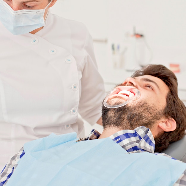 Jeune homme heureux et femme dans un examen dentaire chez dentiste