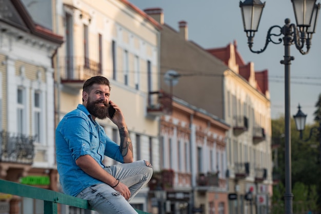 Jeune homme heureux parlant au téléphone portable à l'extérieur