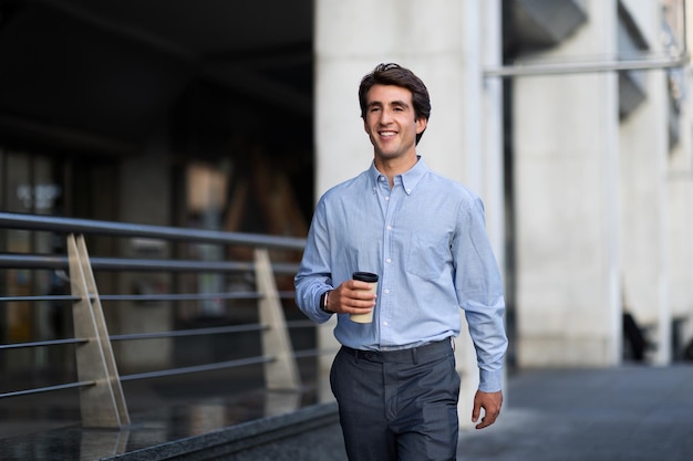 Jeune homme heureux professionnel marchant avec du café à emporter