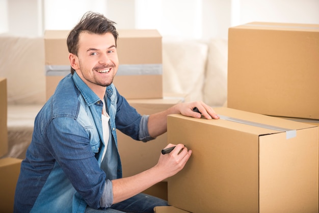 Jeune homme heureux signature boîte dans la nouvelle maison.