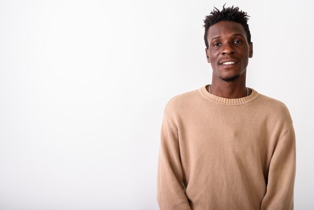 Jeune homme heureux souriant contre le mur blanc