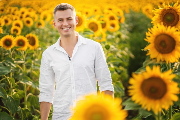 Jeune homme heureux souriant dans le champ de tournesols