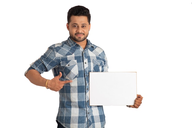 Un jeune homme heureux tenant et affichant un panneau ou une pancarte dans ses mains sur un fond blanc