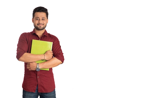 Jeune homme heureux tenant et posant avec le livre sur fond blanc