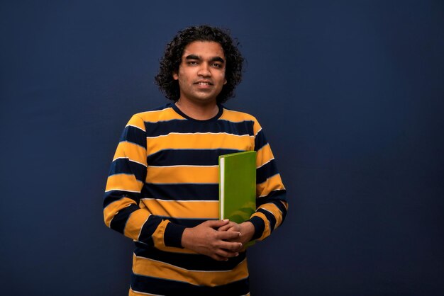 Photo jeune homme heureux tenant et posant avec le livre sur fond gris