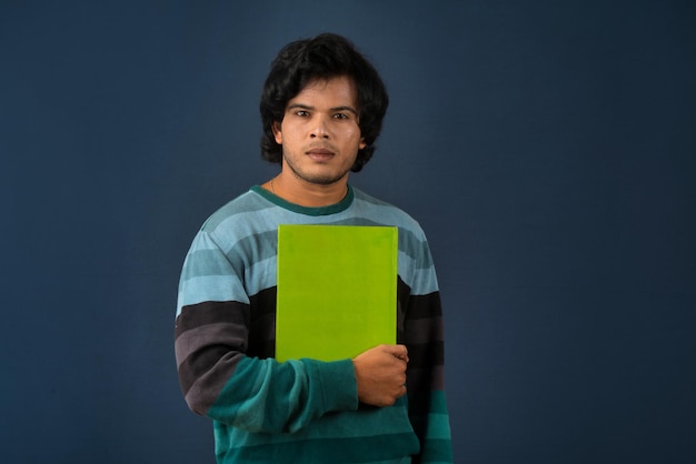 Jeune homme heureux tenant et posant avec le livre sur fond