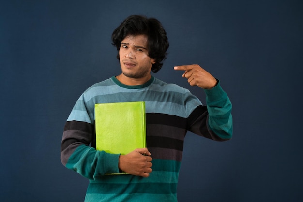 Jeune homme heureux tenant et posant avec le livre sur fond