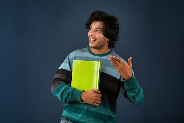 Jeune homme heureux tenant et posant avec le livre sur fond