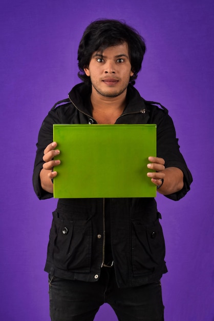 Jeune homme heureux tenant et posant avec le livre sur fond