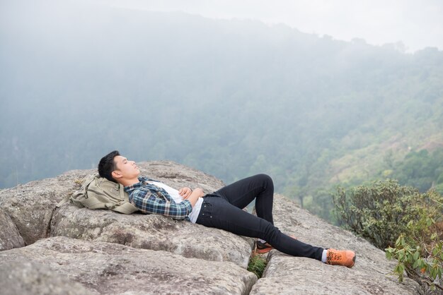 Jeune homme hipster allongé sur les rochers dans les montagnes