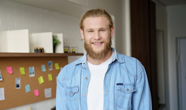 Jeune homme hipster positif, debout au bureau à domicile, regardant la caméra, photo de la tête