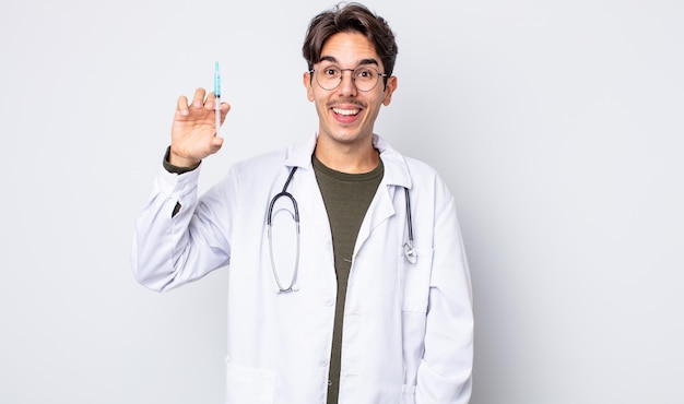 Jeune homme hispanique à l'air heureux et agréablement surpris. concept de seringue de médecin