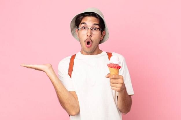 Jeune homme hispanique à l'air surpris et choqué, avec la mâchoire tombée tenant un objet et tenant une glace