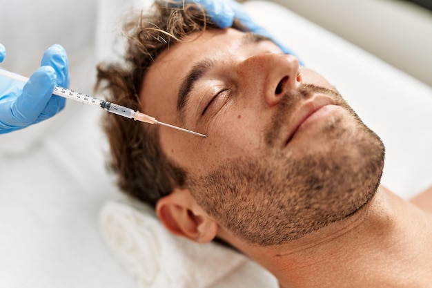 Photo jeune homme hispanique ayant un traitement anti-âge facial au centre de beauté