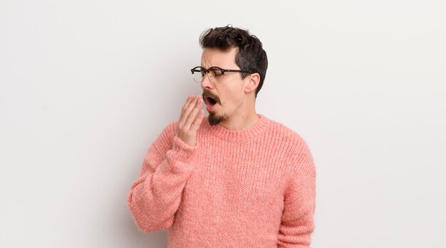 Jeune homme hispanique bâillant paresseusement tôt le matin se réveillant et ayant l'air endormi fatigué et ennuyé