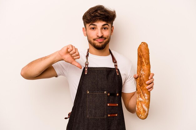 Jeune homme hispanique boulanger isolé sur fond blanc montrant un geste d'aversion pouce vers le bas Concept de désaccord